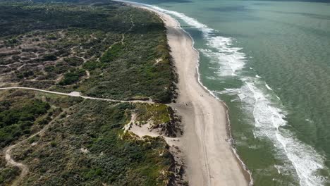 A-beautiful-secluded-beach-with-rolling-waves-and-overgrown-dunes-as-seen-from-high-above