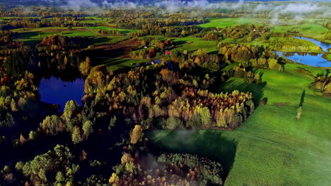 Nebliger-Morgenblick-Auf-Farbenfrohe,-Sonnenbeschienene-Herbstlandschaft-Mit-Bäumen-Und-Seen