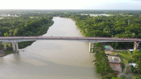 Tracking-Aerial-shot-along-Concrete-Brigde-connecting-two-Forested-riverbanks,-Bangladesh
