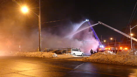 Static-view-of-firemen-and-hydrants-working-to-put-out-a-fire,-in-the-middle-of-a-snowy-road