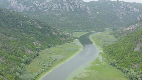 Drone-flying-over-Skadar-lake-inbetween-green-hills-and-mountains,-Montenegro-podgoricia