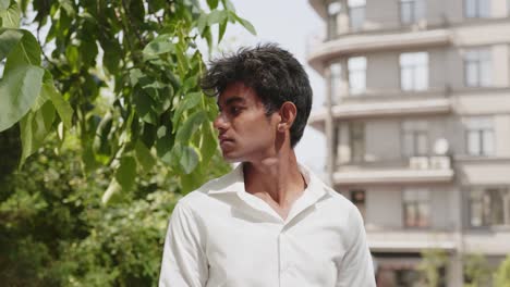Closeup-portrait-of-young-man-wearing-white-shirt-enjoying-time-outside-in-city