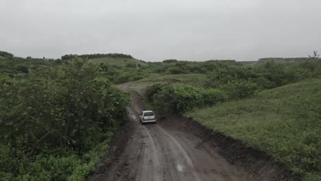 Vehicle-Driving-On-A-Dirt-Road-Leading-Up-The-Mountain-In-Colombia---drone-shot