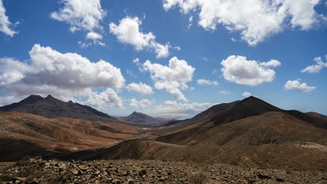 Timelapse-shot-of-puffy-clouds-in-blue-sky-over-barren-mountainous-landscape---Mirador-Astronomico,-Fuerteventura