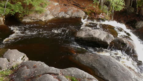 Strong-water-stream-falling-down-rocky-slope,-pan-right-view