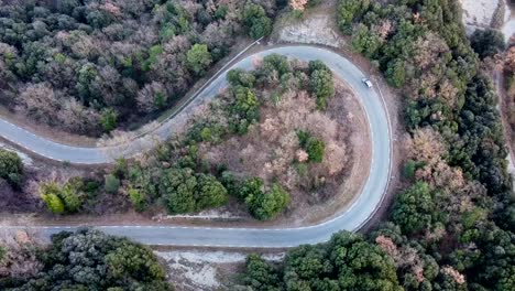 Aerial-view-car-driving-on-European-road-with-hairpin-bend-in-forest