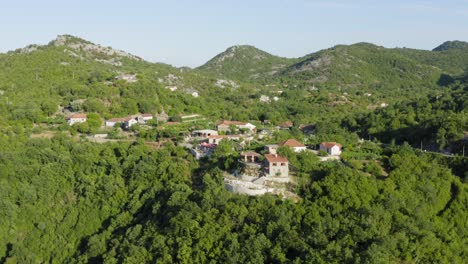 Drone-flying-away-from-hidden-Rural-village-in-Skadar-lake-Montenegro-hidden-between-trees
