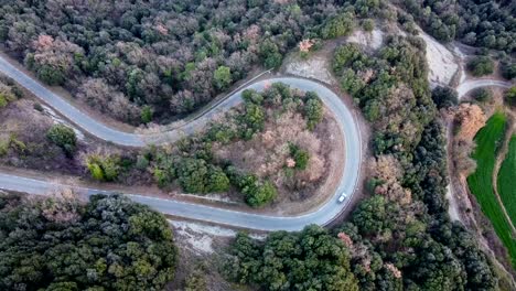 Birds-eye-view-car-driving-on-twisting-snaking-road-in-Catalonia-mountains
