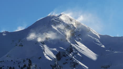 Fresh-snow-powder-blows-off-mountain-peak-at-Avoriaz-Ski-Resort,-French-Alps
