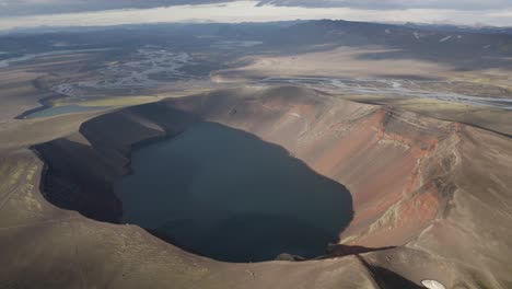 Aerial-backwards-shot-volcanic-landscape-with-crater-lake-in-Iceland---Beautiful-landscape-on-island-during-sunny-day