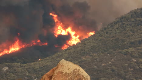 Huge-flames-and-thick-black-smoke-from-the-devastating-Fairview-wildfire,-the-blaze-destroying-all-the-natural-vegetation-on-the-side-of-a-mountain-in-Hemet,-California,-USA