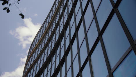 Glasfront-Des-Bürogebäudes-Gegen-Den-Blauen-Himmel-Mit-Vorbeiziehenden-Wolken