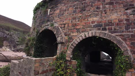 Abandoned-overgrown-Porth-Wen-Welsh-brickwork-dome-furnace-ruins-pull-back-through-archway