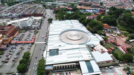 Rotierende-Luftaufnahmen-Rund-Um-Die-Geschäftige-Melaka-Megamall-Mit-Vorbeifahrendem-Verkehr