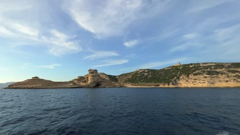 Corsica-island-cliffs-and-Capo-Pertusato-lighthouse-in-France-seen-from-touristic-boat,-slow-motion