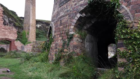 Panorámica-A-Través-De-La-Hierba-De-Porth-Wen-Ruinas-De-Hornos-De-Ladrillo-Abandonados,-Sitio-Industrial-De-Anglesey