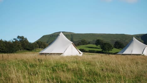 Luxury-bell-tents-in-countryside,-mountains-in-background