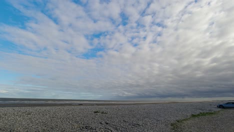 Blue-sky-cloud-cover-time-lapse-passing-over-golden-sandy-Welsh-coastline