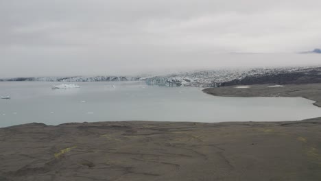 Aerial-panning-shot-of-Breidamerkurjokull-Glacier-with-lake-during-cloudy-day-on-Iceland