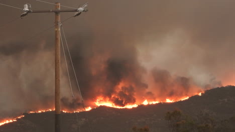 Dramatic-Landscape-of-wildfire-Blazes-on-hillside,-Dark-sky-due-smoke-spead,-Helmet