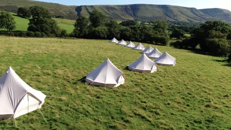 Aerial-filming-of-frontside-luxury-bell-tents-in-Welsh-Countryside,-panning-left-to-right