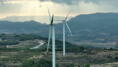 Close-up-view-of-stopped-wind-turbines-and-Spanish-mountains-in-background,-Coll-de-Moro-in-Spain