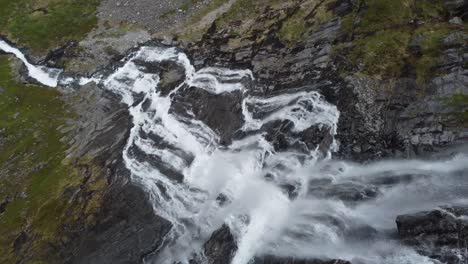 Spectacular-steep-mountain-waterfall-fjellfossen-in-Eidslandet-Vaksdal-Norway---Remote-located-waterfall-stream-falling-far-down-cliffs-in-wilderness-nature---Aerial-following-water-and-turning