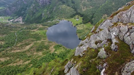Leirovatnet-freshwater-lake-seen-from-tall-mountaintop-cliff---Aerial-moving-sideways-close-to-cliff-creating-massive-parallax-effect---Stunning-view-Eidslandet-Vaksdal-Norway