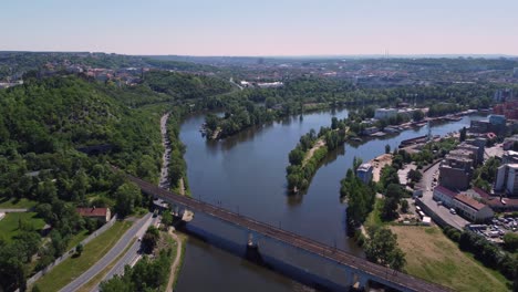 Aerial-drone-view-of-railway-bridge-crossing-Vltava-River-in-Prague,-Czech-Republic,-sunny-day-traffic