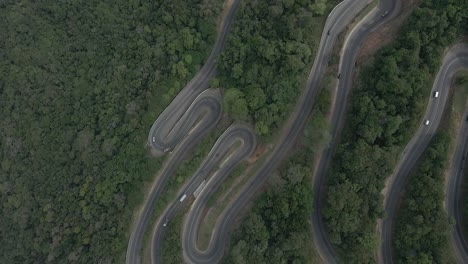 Top-Down-Aerial-Drone-Shot-of-Winding-Highway-Road-on-a-Forest-Mountain-Pass-with-Cars-Driving-on-it