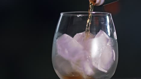Pouring-refreshing-Ice-tea-from-a-bottle-into-a-large-glass-full-of-ice