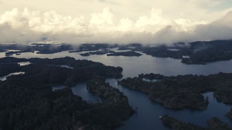 Drone-Aéreo-Sobre-Islas-Lago-Guatape-Medellin-Colombia-Bajo-Niebla-Cielo-Nublado-Paisaje-Escénico