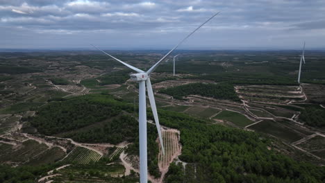 Aerial-drone-orbiting-around-eolic-turbine-and-surrounding-landscape,-Coll-de-Moro-wind-farm,-Catalonia-in-Spain