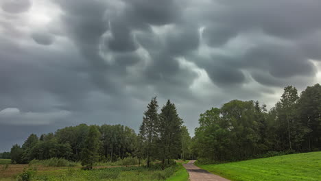 Zeitraffer-Dunkler-Regenwolken,-Die-Sich-über-Grünem-Wald-Und-Landstraße-Bewegen