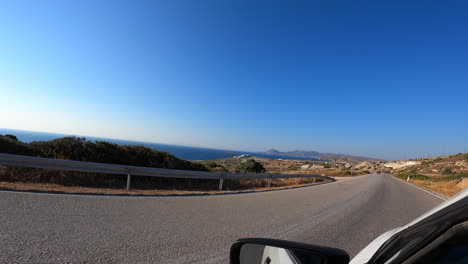 POV:-left-side-with-rear-view-mirror-of-a-white-car-driving-on-a-winding-road-in-Greece,-summer