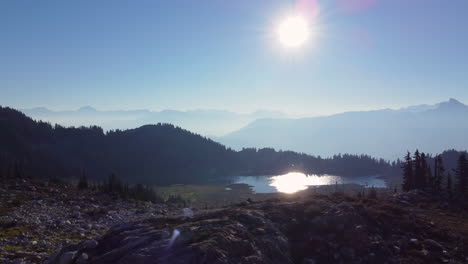 Schöne-Luftenthüllung-Des-Bergspitzensees-Und-Der-Sonne-Mit-Dunstigem-Berglandschaftshintergrund-Auf-Dem-Berggebräu-In-Kanada-Bc-4k
