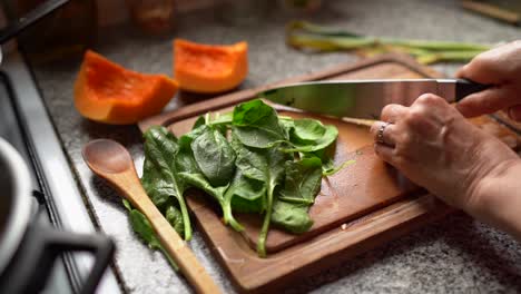 Chopping-Green-Leafy-Spinach-On-Wooden-Board-In-The-Kitchen