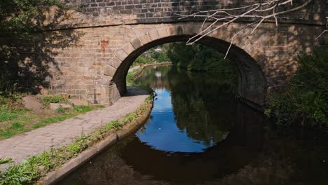 Drone-footage-of-a-canal-with-a-stone-built-bridge-set-in-Todmorden,-Halifax,-West-Yorkshire-England