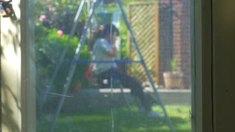 Unrecognisible-girl,-child,-plays-on-English-garden-swing-before-running-off