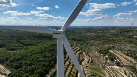 Perspective-close-up-of-wind-turbine-blades-with-countryside-in-background,-Trucafort,-Pradell-de-La-Teixeta,-Tarragona-in-Spain