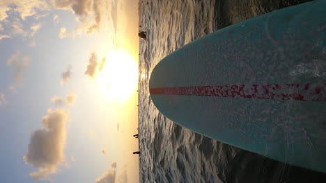 Vertical-Shot-Of-A-Blue-Surfboard-With-Red-Line-Floating-On-Sea-Surface-In-Canggu,-Bali,-Indonesia