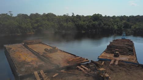 Loading-barges-with-logs-from-the-Amazon-rainforest-to-transport---aerial-flyover