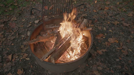 Wide-slow-motion-footage-of-a-fire-in-a-fire-ring-at-a-campground