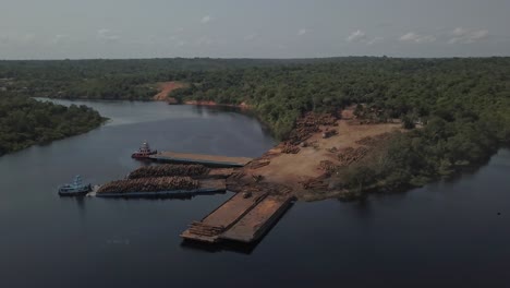 Climate-change-and-deforestation:-loading-logs-from-the-Amazon-rainforest-on-barges-for-transport---aerial-flyover
