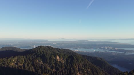 Incredible-Aerial-View-of-Vancouver-Canada-BC-from-Crown-Mountain-with-Mountain-Top-Trees-and-Lone-Wind-Turbine---Pushing-Drone-Shot-4K