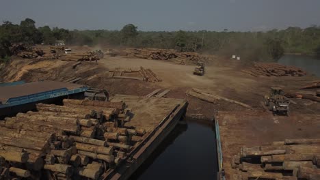 Tractor-loaders-stacking-logs-from-the-Amazon-rainforest-onto-barges---aerial-parallax