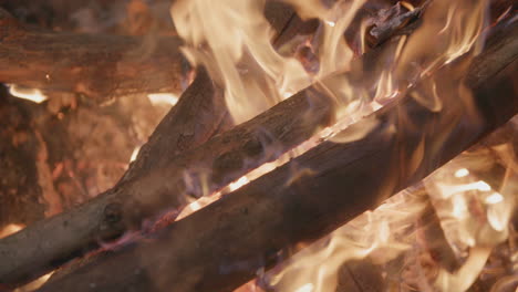 Slow-motion-footage-panning-across-logs-in-a-campfire-in-a-fire-ring-at-a-campground
