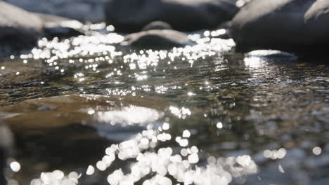 Close-up-slow-motion-footage-of-the-sun-glistening-and-reflecting-off-the-water-in-a-creek
