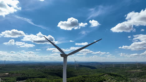 Close-up-of-wind-turbine-blades-spinning-in-blue-sky-with-white-clouds-on-sunny-day,-Coll-de-Moro,-Catalonia-in-Spain