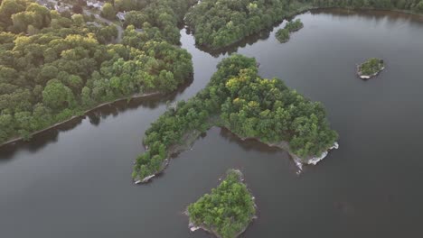 An-aerial-view-over-calm-waters-with-small-islands-with-green-trees-on-a-sunny-day